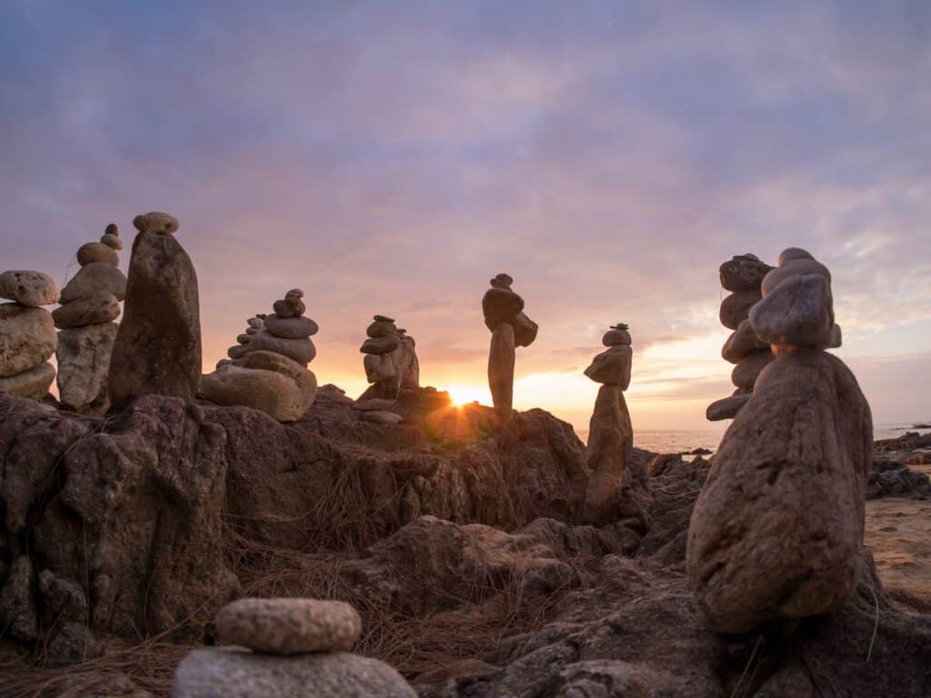 Stones pyramid on sand symbolizing zen, harmony, balance. Ocean at sunset